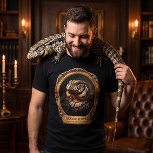 May include: Black t-shirt with a lizard portrait in a gold frame, and the text "SEÑOR JOWLS". A large lizard is draped over the person's shoulders. The background includes a bookshelf and a leather armchair.