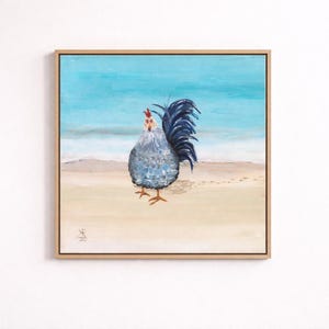 May include: Square framed painting of a rooster on a beach. The rooster has a blue and gray body, a red comb, and a dark blue tail. The background features a light blue sky and ocean, with a sandy beach and footprints.