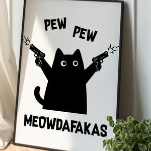 May include: Black and white framed print featuring a cartoon cat silhouette holding two guns, with the words "PEW PEW" above and "MEOWDAFAKAS" below. The cat has large, round eyes and a tail. The print is displayed against a white background.