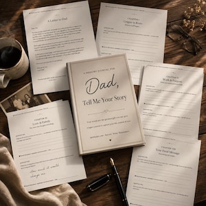 Puede incluir: Un diario de recuerdos titulado "Dad, Tell Me Your Story" con una cubierta color crema y letras doradas, rodeado de hojas sueltas, un bolígrafo y una taza de café. El diario está diseñado para capturar historias de vida.