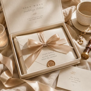 May include: A cream-colored box set of wedding letters, tied with a satin ribbon. The box reads "OPEN WHEN wedding letters" and "A collection of love, for every moment." One envelope reads "OPEN WHEN you feel nervous before the ceremony."