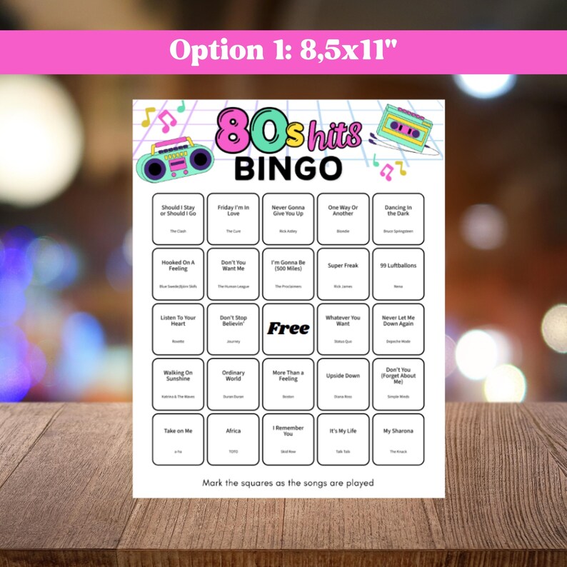 May include: A white 80s Hits Bingo game card with a pink and teal design. The card features song titles in boxes, a boombox graphic, and the text "Option 1: 8.5x11". The card is on a wooden surface.