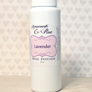 May include: White plastic bottle with a label that says "Amaranth & Rue Lavender Body Powder 8 oz". The label also lists the ingredients: Arrowroot Powder, Kaolin Clay, Lavender Essential Oil, Lemongrass Essential Oil, Aspen Bark Extract.
