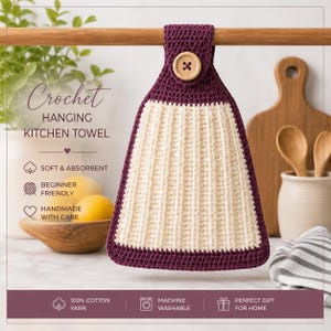 Op de afbeelding: Een hangende keukendoek met een crèmekleurig geribbeld middenpaneel omrand door een donkerpaarse gehaakte rand. Het bovenste gedeelte bevat een bijpassende donkerpaarse gehaakte lus die is vastgezet met een enkele lichtbruine houten knoop.