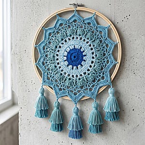 May include: A blue and white crochet mandala wall hanging. The circular design features intricate patterns and is framed by a wooden embroidery hoop. Six blue tassels hang from the bottom. This handmade piece adds a bohemian touch to any space.