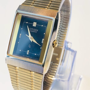 Peut inclure: Montre Citizen Quartz vintage avec un boîtier rectangulaire doré et un cadran bleu foncé. La montre présente des aiguilles et des index dorés, ainsi qu'un bracelet souple doré. Le cadran affiche le texte "CITIZEN QUARTZ".