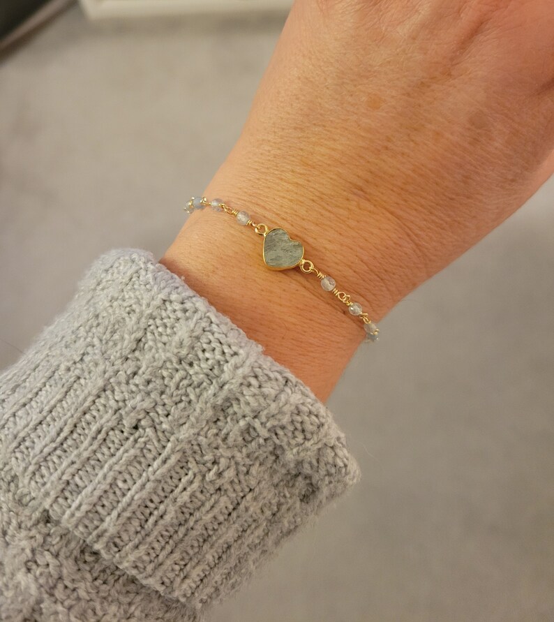May include: A gold chain bracelet with a light blue heart-shaped charm and small light blue beads.