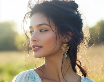 May include: A woman with long dark hair wearing a white floral dress and gold earrings with turquoise accents. The earrings are triangular in shape and have a geometric design.