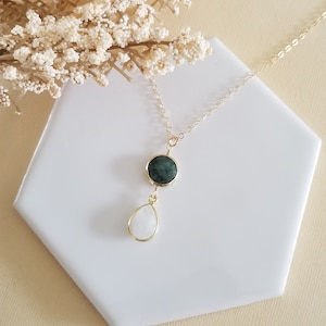 May include: A gold chain necklace featuring a circular dark green stone pendant connected to a teardrop-shaped white stone pendant. The necklace is constructed with thin gold metal links and gold wire settings that secure both stones in a vertical arrangement.