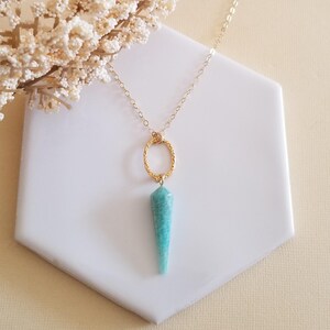 May include: A gold chain necklace with a turquoise gemstone pendant and a gold circle charm.