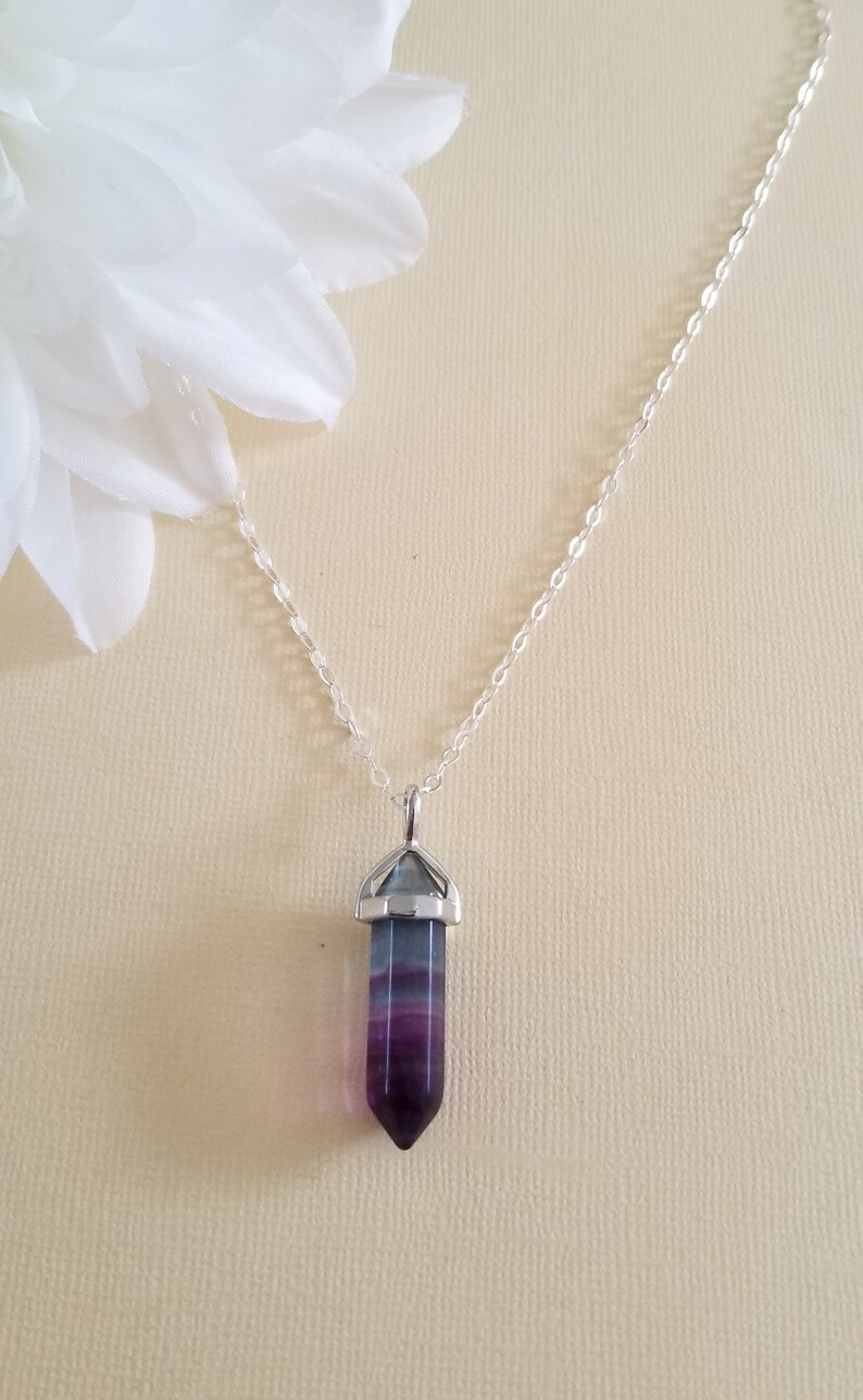 May include: A silver chain necklace with a purple and green crystal point pendant.