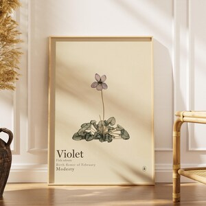 May include: A rectangular wall art print on a light beige background featuring a botanical illustration of a single violet flower with green leaves. The text reads Violet, Viola odorata, Birth flower of February, and Modesty in black font.