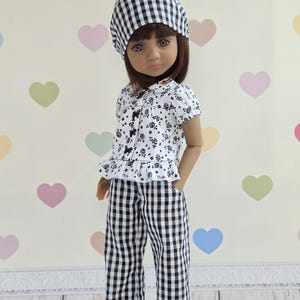 May include: A doll wearing a black and white gingham headscarf, a white short-sleeved blouse with a black floral print and small black bows, and matching black and white gingham trousers. The text Dollsgarmentlily is visible in the top left corner.