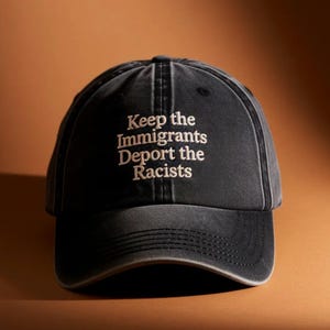 May include: A charcoal black baseball cap with a distressed, washed-out finish. The front panel features embroidered off-white text that reads: Keep the Immigrants Deport the Racists. The cap has a curved brim and a structured six-panel design.