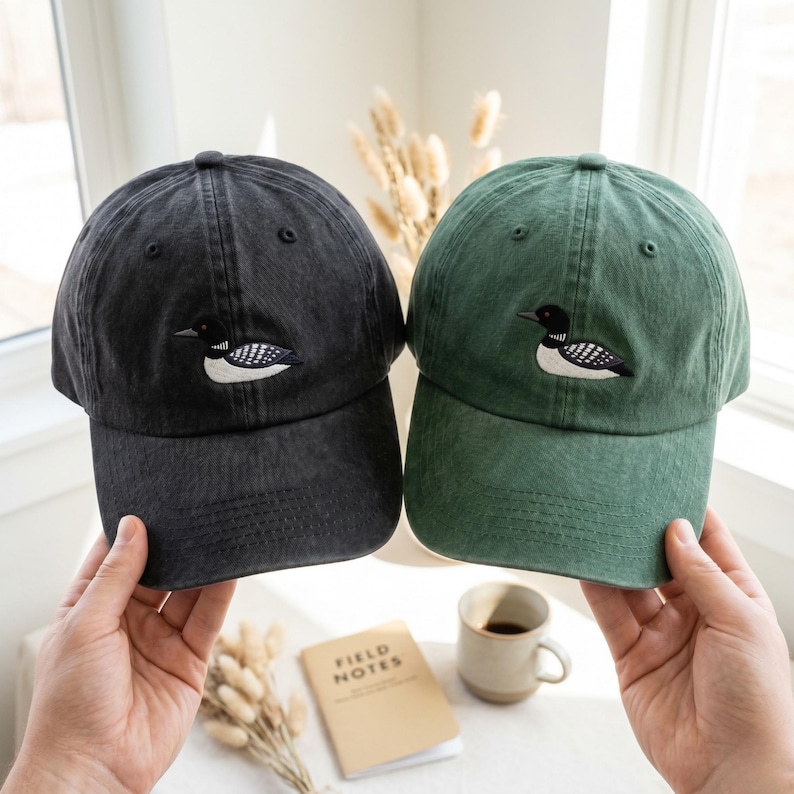 Pu&ograve; includere: Due cappellini da baseball, uno grigio antracite e uno verde bosco, ciascuno con una toppa ricamata raffigurante un colimbo nero e bianco sul pannello frontale. Entrambi i cappellini presentano una corona strutturata e una visiera curva.