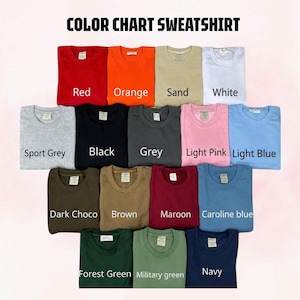 May include: A color chart for sweatshirts featuring seventeen folded crewneck garments in various shades including red, orange, sand, white, sport grey, black, grey, light pink, light blue, dark choco, brown, maroon, caroline blue, forest green, military green, and navy.