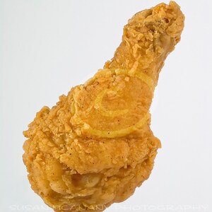 Pode incluir: Um pedaço de frango frito crocante e dourado.