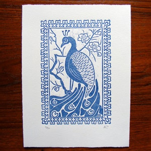 May include: A blue and white print of a peacock with its tail feathers spread out. The print is framed with a decorative border and has the text "39/50" and "R.T." in the bottom corners.