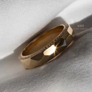May include: Modern faceted men's wedding band crafted in solid 14K yellow gold featuring a geometric exterior and pavé-set lab diamonds along one side of the band. The text "BY ADITISILVERJEWELUS" is visible at the bottom.