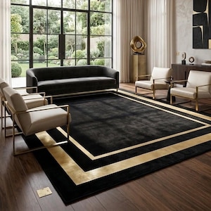 May include: An elegant living room with a black rug featuring gold borders, a dark grey sofa, and cream armchairs with gold frames. Large windows provide a view of a garden, creating a sophisticated and inviting atmosphere.