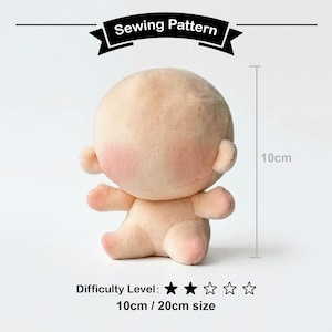 Puede incluir: Patrón de costura de muñeco de peluche beige con mejillas rosas, de 10 cm de altura. El nivel de dificultad es de dos estrellas sobre cinco. El texto "Sewing Pattern" se muestra encima del muñeco.