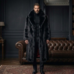 May include: A full-length black faux fur coat with a wide collar. The coat is worn over a black turtleneck and pants. The background features a dark interior with a leather sofa and a patterned rug.