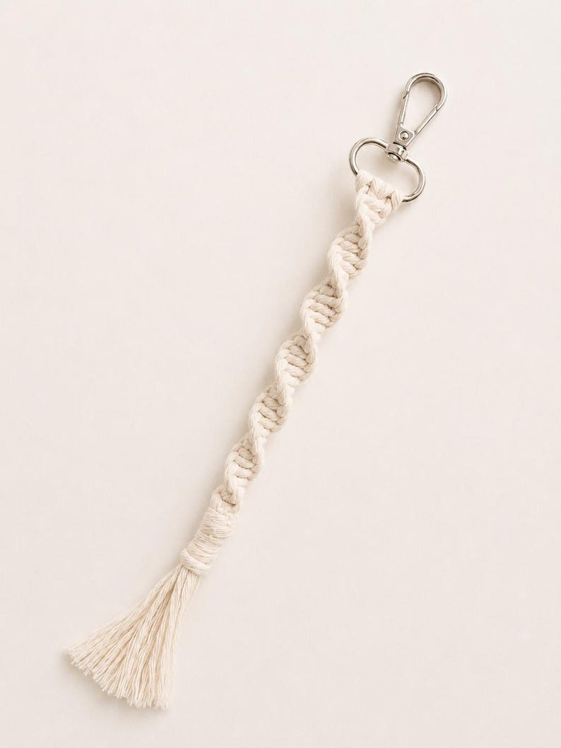 Puede incluir: Llavero de macram&eacute; color crema con cierre plateado. El llavero presenta un dise&ntilde;o de cuerda trenzada y una borla en el extremo. Accesorio hecho a mano para llaves o bolsos.