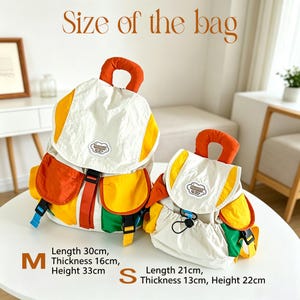 May include: Two backpacks in medium and small sizes, featuring a cream, yellow, orange, and green colour scheme. The medium bag measures 30cm long, 16cm thick, and 33cm high. The small bag measures 21cm long, 13cm thick, and 22cm high.