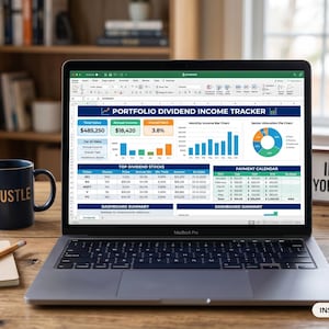 May include: A laptop displays a "Portfolio Dividend Income Tracker" spreadsheet. A blue mug with "HUSTLE" is next to the laptop. A sign reads "INVEST IN YOUR FUTURE". A succulent plant and a notepad with a pencil are also on the wooden desk.