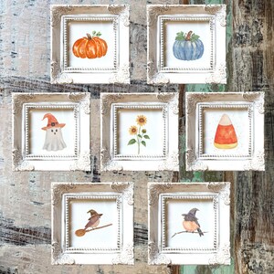 May include: A collection of seven square, ornate, distressed white frames, each containing a watercolor illustration. The images feature an orange pumpkin, a blue pumpkin, a ghost in a hat, sunflowers, a candy corn, a bird on a broom, and a bird in a hat.