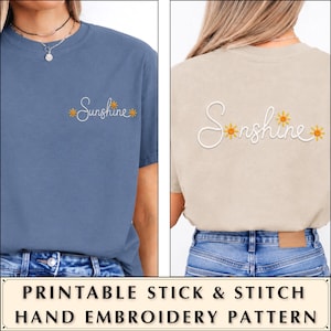 Puede incluir: Una camiseta azul con la palabra Sunshine bordada en letra cursiva blanca en el pecho, y una camiseta beige con la misma palabra e iconos de sol amarillos bordados en mayor tamaño en la espalda, ambas combinadas con pantalones vaqueros.