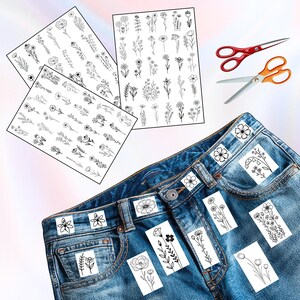 May include: Three sheets of black and white floral stickers with various flower designs. A pair of red and orange scissors are next to a pair of blue jeans with floral stickers on the pockets. The stickers are for DIY crafts.