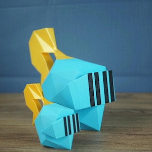 Puede incluir: Dos cascos de caballero low-poly en color cian brillante con crestas amarillas y barras de visera verticales negras. El casco más grande está colocado detrás del más pequeño, ambos con superficies geométricas facetadas y angulares.