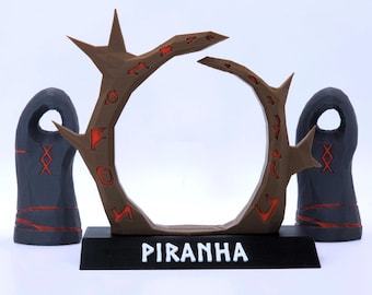 May include: A brown circular frame with sharp, thorn-like protrusions and red recessed markings, mounted on a black rectangular base labelled PIRANHA in white text, flanked by two dark grey, rounded, pillar-like objects with red rune-like symbols.