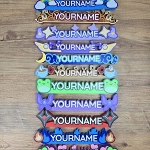 May include: A collection of colorful, decorative nameplates with various designs, including a bear, rainbow, stars, and flames. Each nameplate features the word "YOURNAME" in a bold font, perfect for personalization.