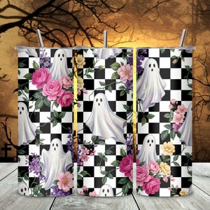 May include: A cylindrical tumbler featuring a black and white checkered pattern overlaid with illustrations of white ghosts, pink roses, and small yellow and purple flowers. The design includes a thin metal straw extending from the top opening.