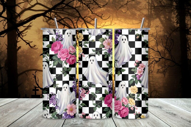 May include: A cylindrical tumbler featuring a black and white checkered pattern overlaid with illustrations of white ghosts, pink roses, and small yellow and purple flowers. The design includes a thin metal straw extending from the top opening.