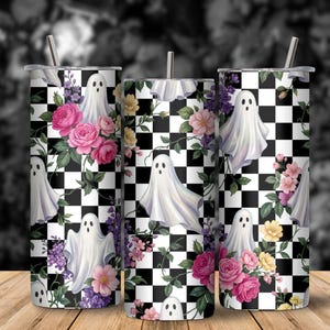 May include: Three cylindrical tumblers featuring a black and white checkered pattern overlaid with illustrations of white ghosts, pink roses, and purple flowers. Each tumbler includes a thin metal straw inserted into the top lid.