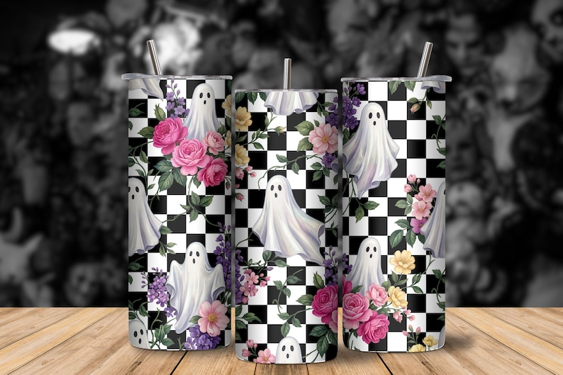 May include: Three cylindrical tumblers featuring a black and white checkered pattern overlaid with illustrations of white ghosts, pink roses, and purple flowers. Each tumbler includes a thin metal straw inserted into the top lid.