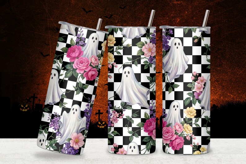 May include: Three cylindrical tumblers with metal straws featuring a black and white checkered pattern overlaid with illustrations of white ghosts, pink roses, purple flowers, and green leaves. The design wraps around the entire surface of each cup.