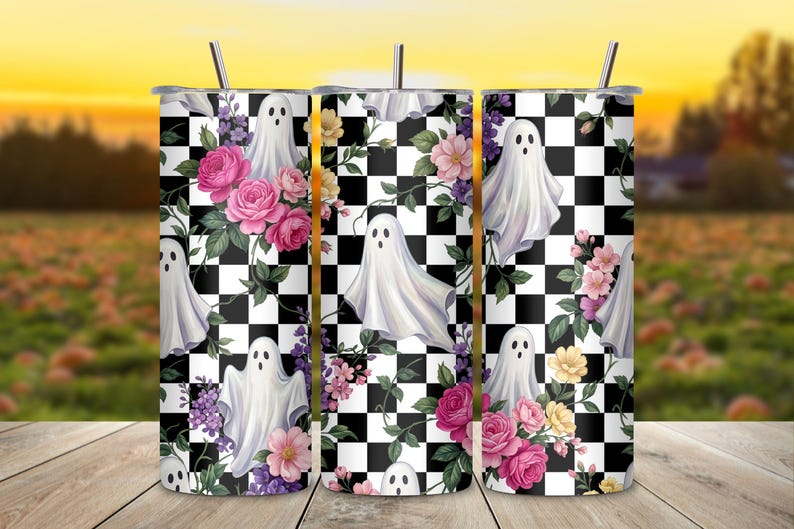 May include: A cylindrical stainless steel tumbler with a straw, featuring a repeating pattern of white ghosts, pink and yellow roses, and purple flowers set against a black and white checkered background. The design wraps around the entire vessel.
