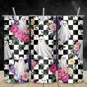 May include: A cylindrical tumbler with a straw featuring a repeating pattern of white ghosts, pink and yellow flowers, green leaves, and a black and white checkerboard background. The design covers the entire surface of the metal drink container.