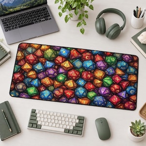 May include: A rectangular desk mat featuring a dense, colorful pattern of multi-faceted polyhedral dice in shades of red, blue, green, purple, and orange, each marked with gold-colored symbols and numbers, set on a light-colored desk surface.