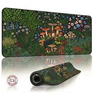 Puede incluir: Alfombrilla de escritorio rectangular negra con una detallada ilustración de una escena de bosque con setas, bayas y varias plantas. La alfombrilla está enrollada en primer plano, mostrando el diseño. La paleta de colores incluye verdes, marrones, rojos y azules.