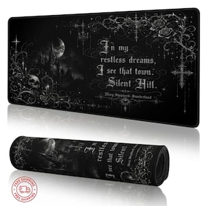 May include: Black rectangular desk mat with a gothic design. The mat features a castle, moon, skulls, roses, and the text "In my restless dreams, I see that town. Silent Hill." A rolled-up version is also shown.