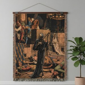 Könnte beinhalten: Gewebte Tapisserie mit einer detaillierten, Vintage-Illustration einer skelettartigen Figur, die inmitten einer Szene von Tod und Verzweiflung Geige spielt. Das Kunstwerk ist in Braun-, Schwarz- und Blautönen gehalten und hat einen Fransenrand.