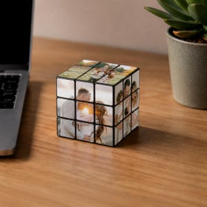 Puede incluir: Un cubo de Rubik en blanco y negro con fotos personalizadas de una pareja y una familia. El cubo está sobre una superficie de madera, junto a un portátil y una suculenta en maceta. Las fotos muestran a una pareja besándose y a otros miembros de la familia.