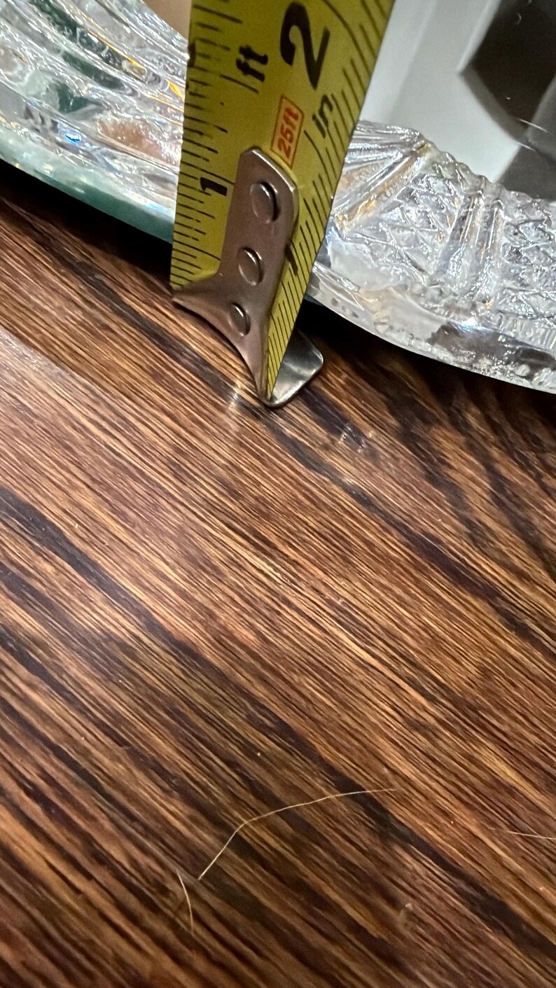 May include: A clear glass tray with a textured, geometric pattern along the rim. A yellow metal measuring tape is positioned against the edge of the tray, indicating a thickness of approximately 0.6 centimetres for the glass rim.