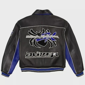 May include: A black leather varsity jacket featuring blue side panels and a ribbed hem with blue and white stripes. The back displays a large graphic of a black spider with the text Black Spider and the brand name Avirex in white and blue.