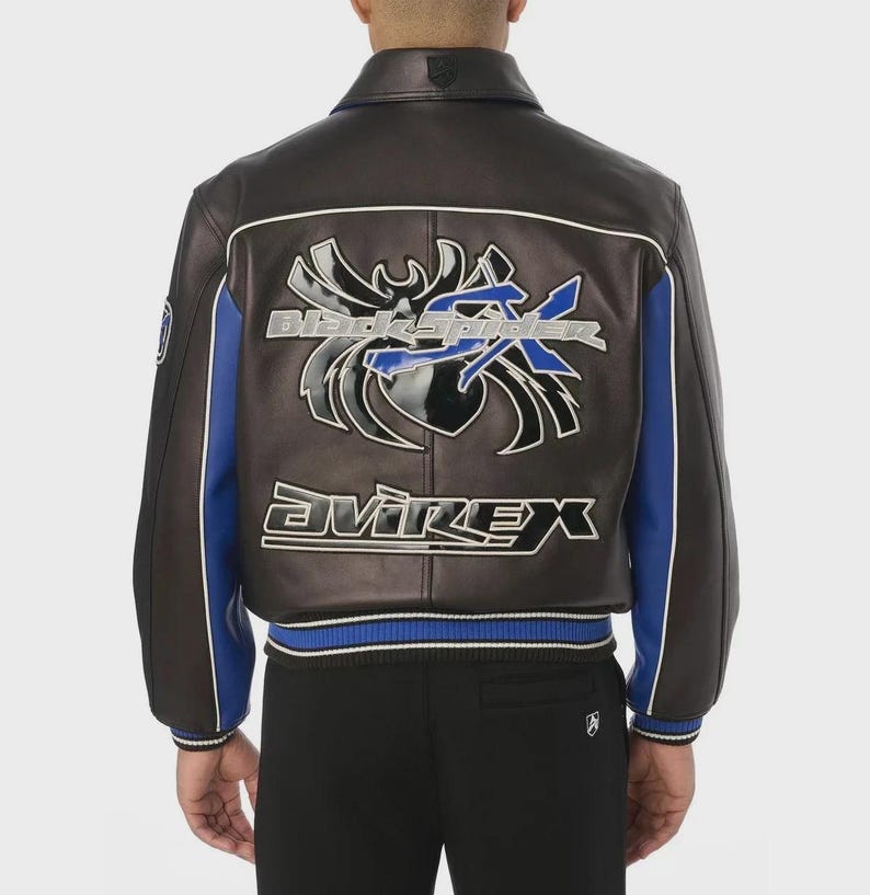 May include: A dark brown leather jacket featuring blue side panels and white piping. The back displays a large, glossy black spider graphic with the blue text "Black Spider" and the white text "Avirex" printed in a bold, stylized font.